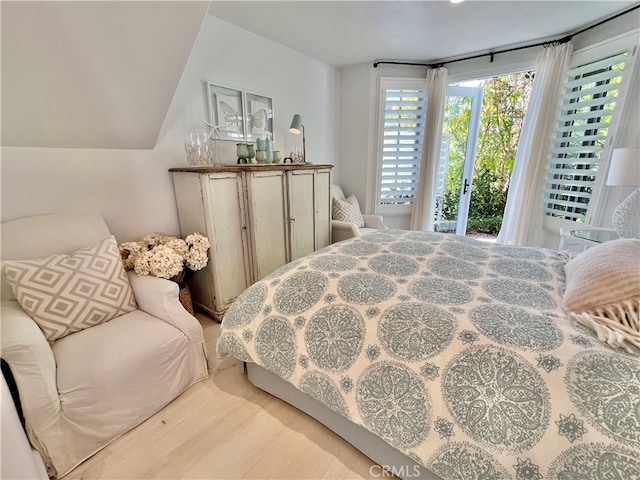 bedroom featuring lofted ceiling, hardwood / wood-style floors, and access to exterior