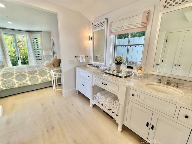 bathroom with wood-type flooring, vaulted ceiling, and vanity