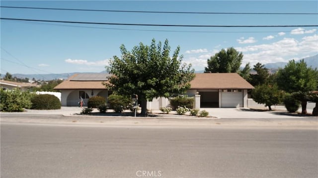 view of front of property with a mountain view, solar panels, and a garage