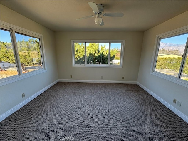 unfurnished room with ceiling fan, dark carpet, and a healthy amount of sunlight