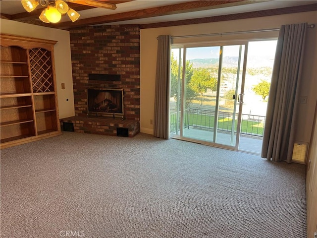 unfurnished living room with ceiling fan, a brick fireplace, beamed ceiling, and carpet floors