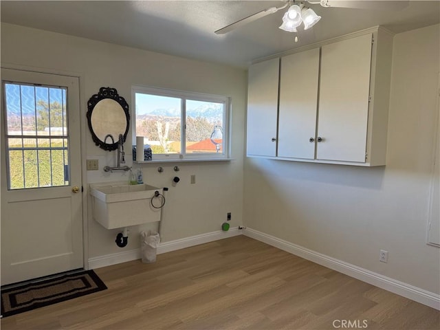 laundry area with washer hookup, cabinets, light hardwood / wood-style floors, and ceiling fan