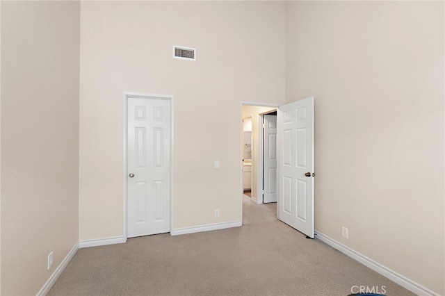 unfurnished bedroom with a high ceiling and light carpet