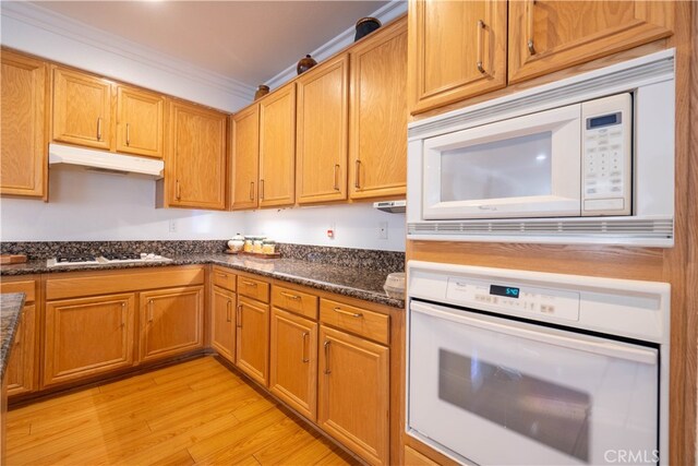 kitchen with light hardwood / wood-style flooring, white appliances, ornamental molding, and dark stone counters