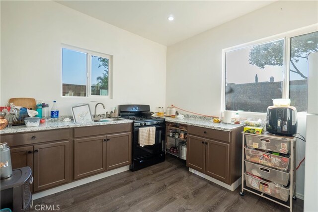 kitchen featuring gas stove, light stone countertops, dark hardwood / wood-style flooring, and a wealth of natural light