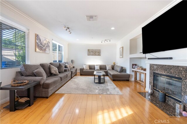 living room with light hardwood / wood-style flooring, ornamental molding, and a high end fireplace