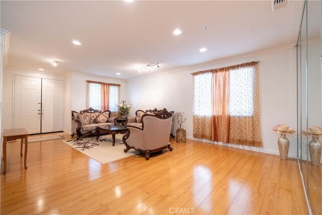 living room featuring crown molding and light hardwood / wood-style flooring