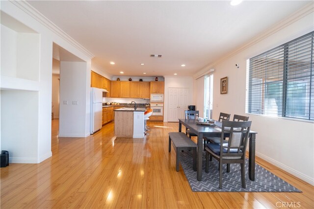 dining space with light wood-type flooring and ornamental molding