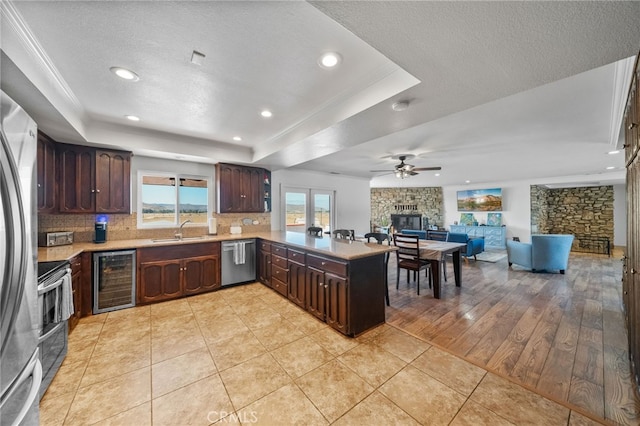 kitchen with wine cooler, sink, kitchen peninsula, stainless steel appliances, and light wood-type flooring