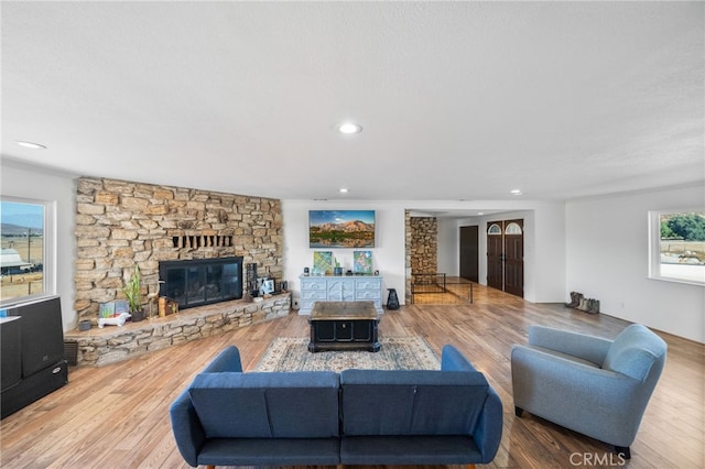 living room featuring a stone fireplace, hardwood / wood-style floors, and plenty of natural light