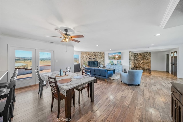 dining area featuring ceiling fan, ornamental molding, wood-type flooring, french doors, and a fireplace