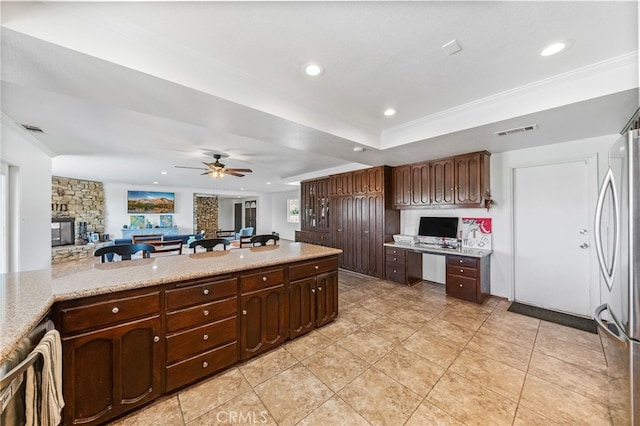 kitchen featuring stainless steel fridge, a fireplace, ceiling fan, and a wealth of natural light