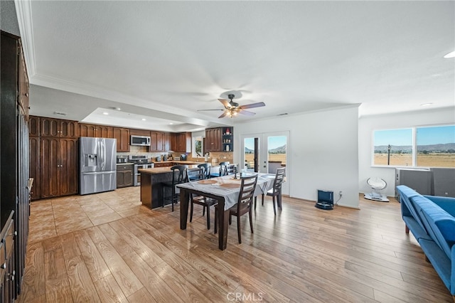 dining space featuring light wood-type flooring, ornamental molding, and ceiling fan