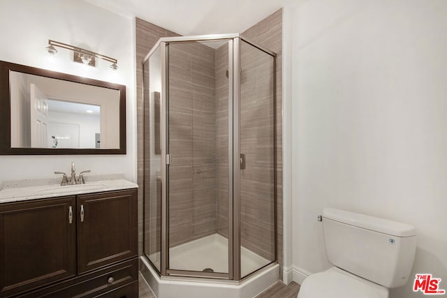 bathroom with a shower with shower door, vanity, and toilet