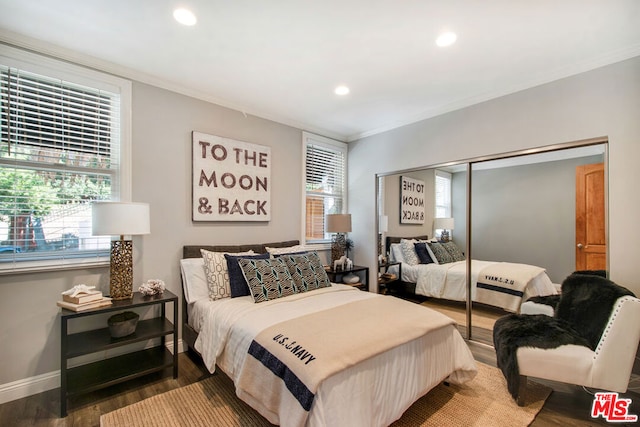 bedroom with multiple windows, ornamental molding, dark wood-type flooring, and a closet