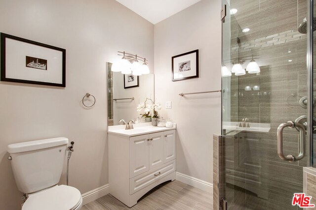 bathroom featuring hardwood / wood-style floors, vanity, toilet, and a shower with shower door