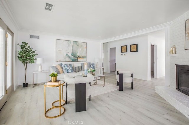 living room featuring light wood-type flooring, plenty of natural light, a fireplace, and crown molding