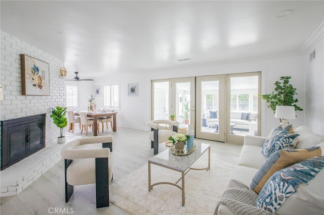 living room with light hardwood / wood-style flooring, a brick fireplace, ceiling fan, and plenty of natural light