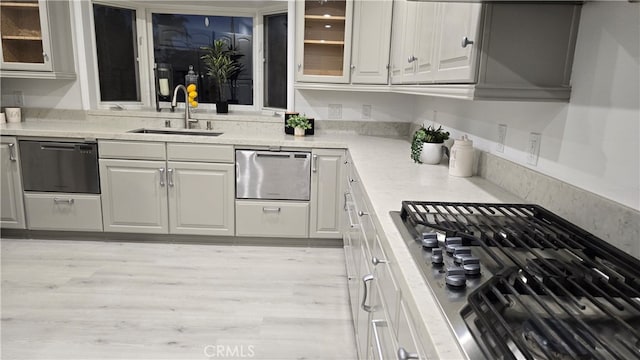 kitchen with dishwasher, light wood-type flooring, sink, and gas stovetop