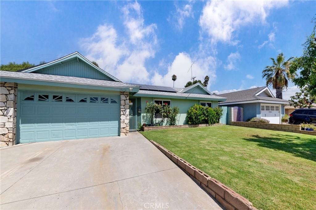 ranch-style home featuring a front lawn, a garage, and solar panels