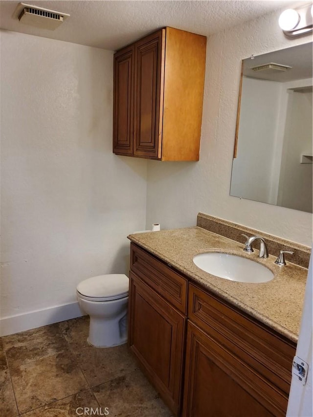 bathroom with a textured ceiling, vanity, and toilet