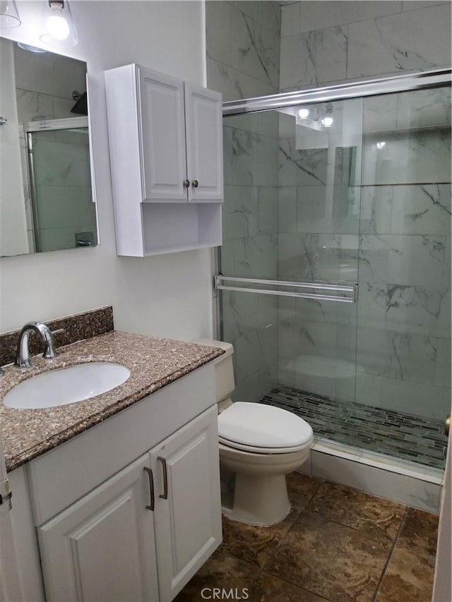 bathroom featuring vanity, toilet, and a shower with door