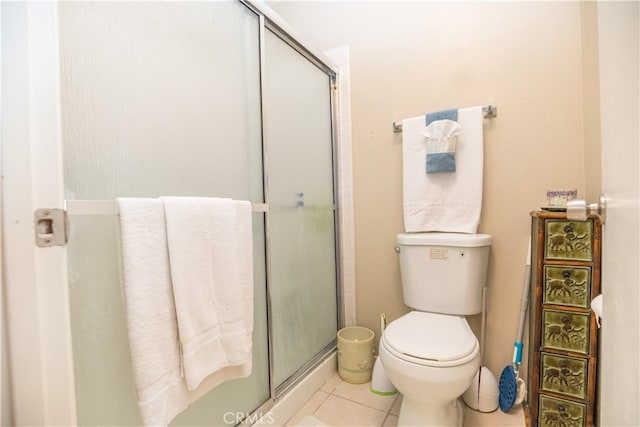 bathroom featuring tile patterned flooring, toilet, and a shower with shower door