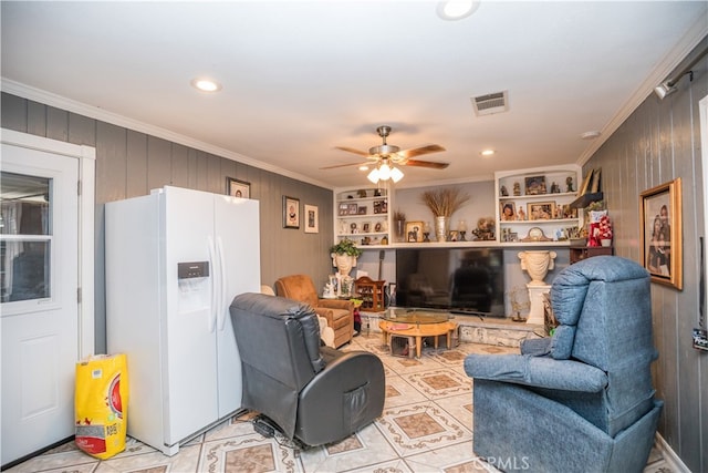 tiled living room with crown molding, wooden walls, and ceiling fan