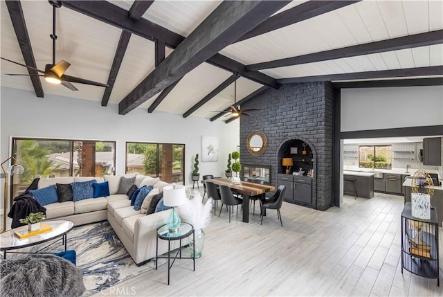 living room featuring lofted ceiling with beams, light hardwood / wood-style floors, and a fireplace