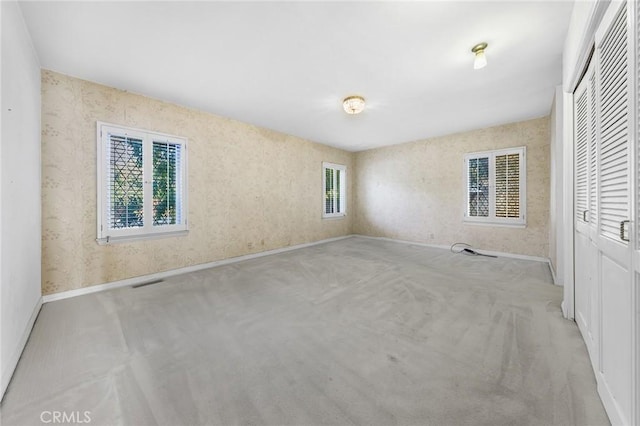 unfurnished bedroom featuring a closet and light colored carpet