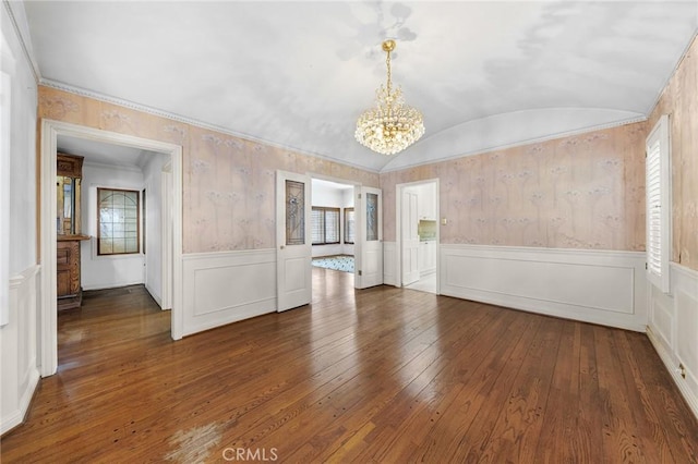 empty room featuring ornamental molding, dark wood-type flooring, vaulted ceiling, and a notable chandelier