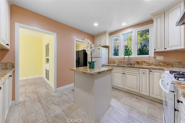 kitchen featuring light stone countertops, sink, wall chimney range hood, white appliances, and a kitchen island