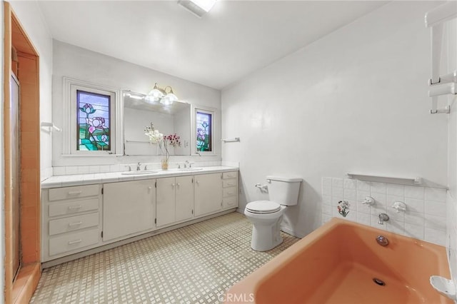 bathroom featuring tile patterned floors, vanity, a bath, and toilet