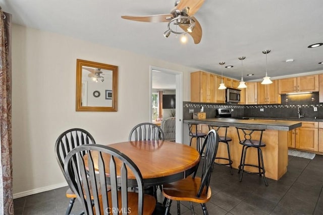 dining space featuring dark tile patterned flooring, ceiling fan, and sink