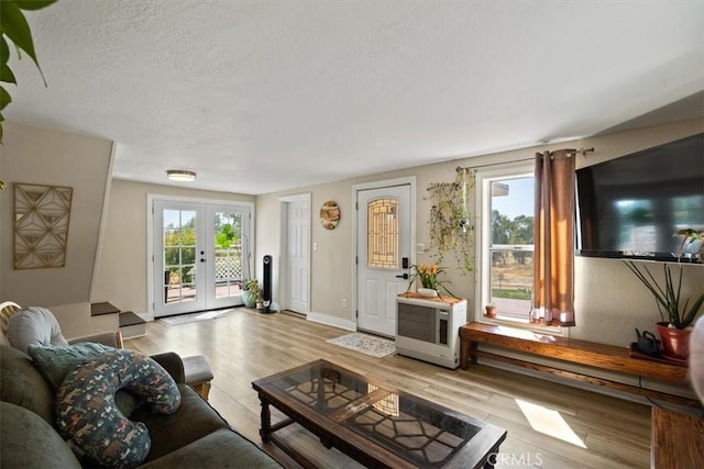 living room featuring a textured ceiling, light hardwood / wood-style flooring, a healthy amount of sunlight, and french doors