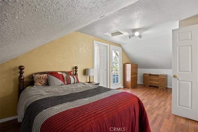 bedroom with hardwood / wood-style flooring, a textured ceiling, and vaulted ceiling