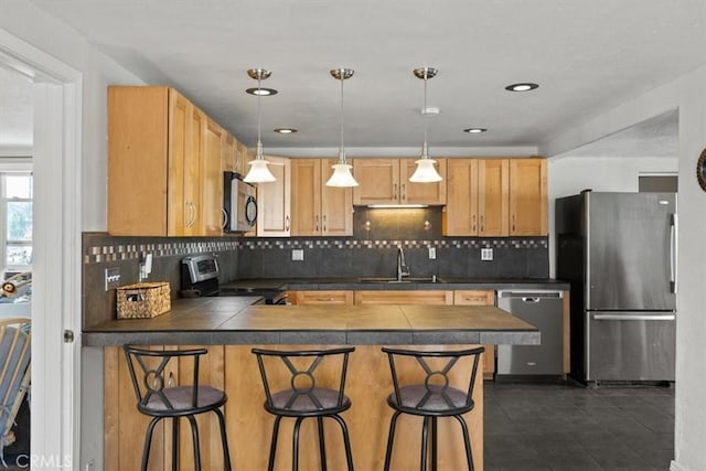 kitchen with a kitchen bar, appliances with stainless steel finishes, decorative backsplash, and sink