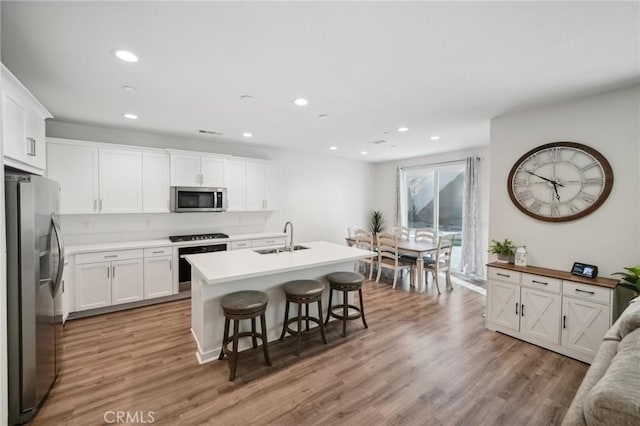 kitchen with white cabinets, an island with sink, stainless steel appliances, and sink