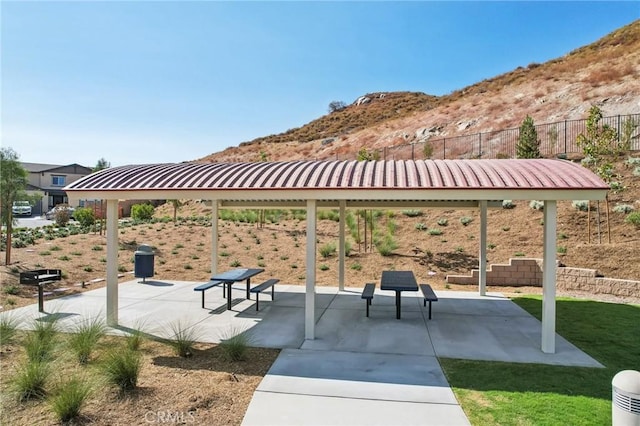 view of property's community with a mountain view, a patio, and a lawn