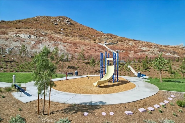 view of jungle gym featuring a mountain view and a yard