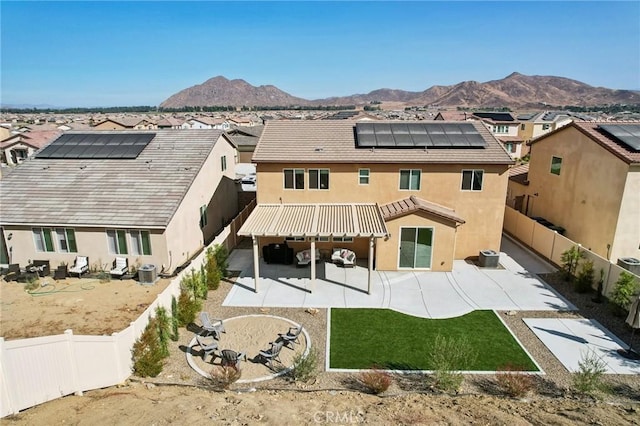 rear view of house with a mountain view, solar panels, a patio, and central AC