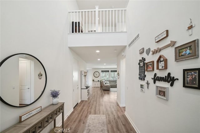 hallway featuring a towering ceiling and light hardwood / wood-style floors