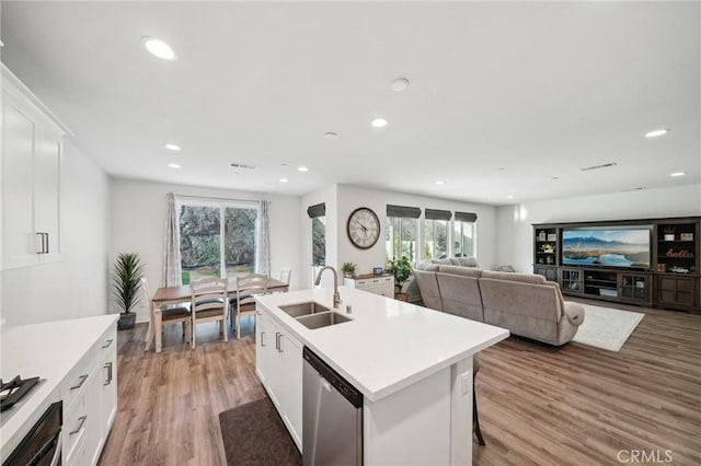 kitchen featuring sink, light hardwood / wood-style flooring, dishwasher, white cabinetry, and an island with sink