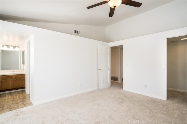 unfurnished bedroom featuring light carpet, lofted ceiling, ceiling fan, and ensuite bathroom