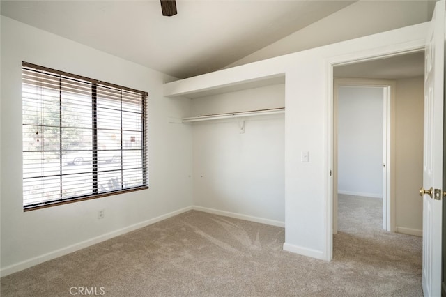 unfurnished bedroom featuring light carpet, a closet, lofted ceiling, and ceiling fan