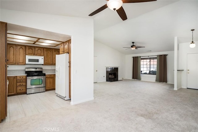 34578 Hickory Ln, Wildomar, CA 92595 - kitchen with white appliances, brown cabinetry, a ceiling fan, light carpet, and vaulted ceiling