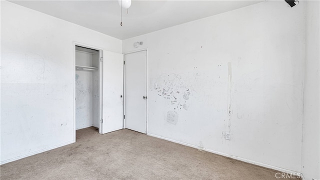 unfurnished bedroom featuring light carpet and a closet