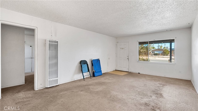 unfurnished room featuring a textured ceiling and light colored carpet