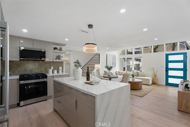 kitchen with pendant lighting, a center island, stainless steel appliances, and light hardwood / wood-style floors