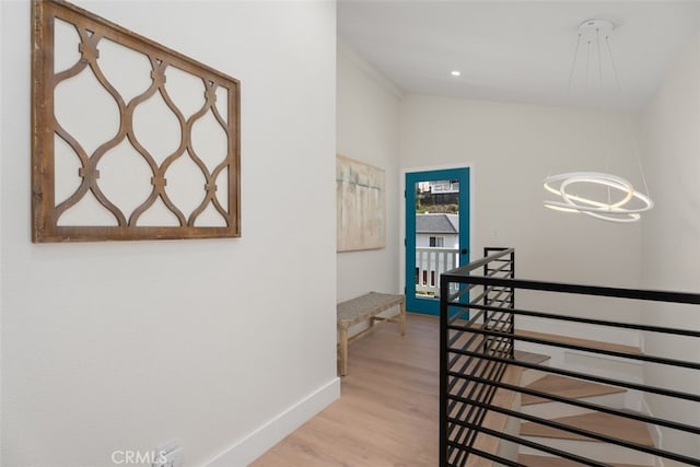 corridor featuring vaulted ceiling, an inviting chandelier, and light hardwood / wood-style flooring